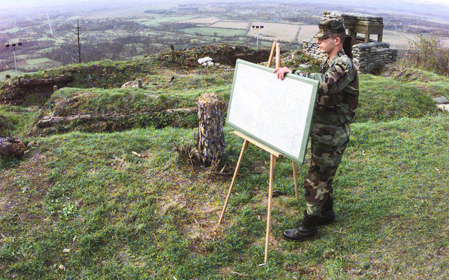 Sgt. Bruno Morra, assigned to A-Battery 4th Battalion 5th Air Defense Artillery, places a map in preparation for a VIP briefing that was to be given later in the day on top of Mount Vis, overlooking the Tuzla Valley. The trenches in the background were used by Bosnian Serb troops who held the position for about three years during the Bosnian civil war before surrendering it to NATO forces in early 1996.