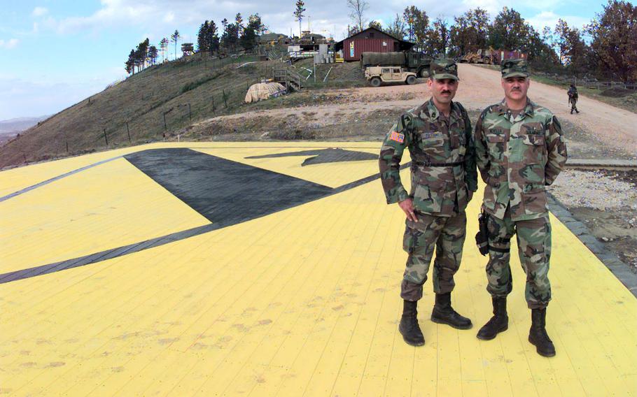 Sgt. 1st Class Fidel Feliciano, left, and Staff Sgt. Robert Novella stand on the largest 1st Cavalry Division patch in Bosnia as they pose for a photo to send home to their loved ones in November, 1998. The patch -- 35 feet, 8 inches wide by 51 feet, 8 inches long -- is painted on the helicopter pad at the outpost on 450-foot Mount Vis.