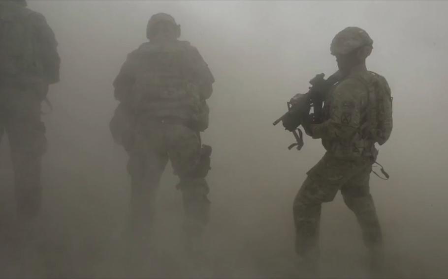 A video screen grab shows Dragon Troop soldiers walking through dust churned up by a nearby helicopter during their deployment to Logar province, Afghanistan, in September 2014.