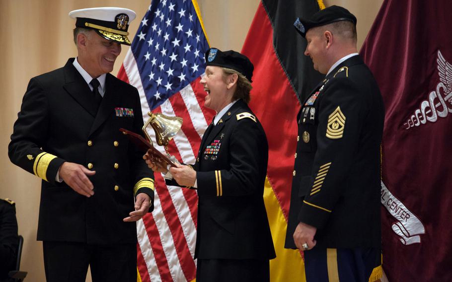 Landstuhl Regional Medical Center's commander, Col. Judith Lee, laughs as Rear Adm. Thomas E. Beeman presents her an official Navy Bell during a ceremony Friday, Sept. 26, 2014, marking the inactivation of the Navy Expeditionary Medical Unit and a transfer of the unit's responsibilities to the 4215th U.S. Army Hospital.