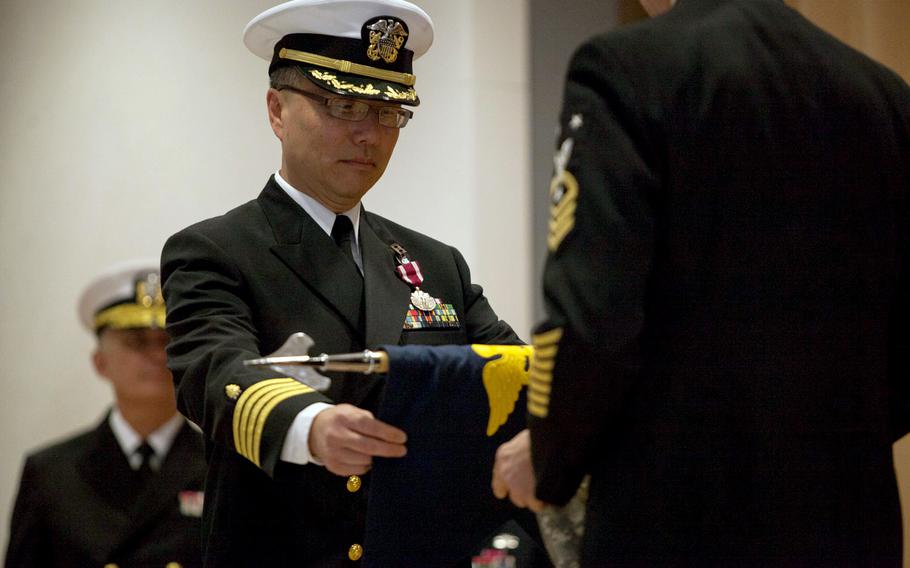Navy Capt. Donald Sze helps roll up and case the colors of the Navy Expeditionary Medical Unit at Landstuhl Regional Medical Center in Germany, during a ceremony marking the end of the unit Friday, Sept. 26, 2014. The Navy first deployed to Landstuhl in 2006, and has since managed the coordination of care and transportation for sick and wounded personnel airlifted from the last decade's wars. That job now falls back to the Army.