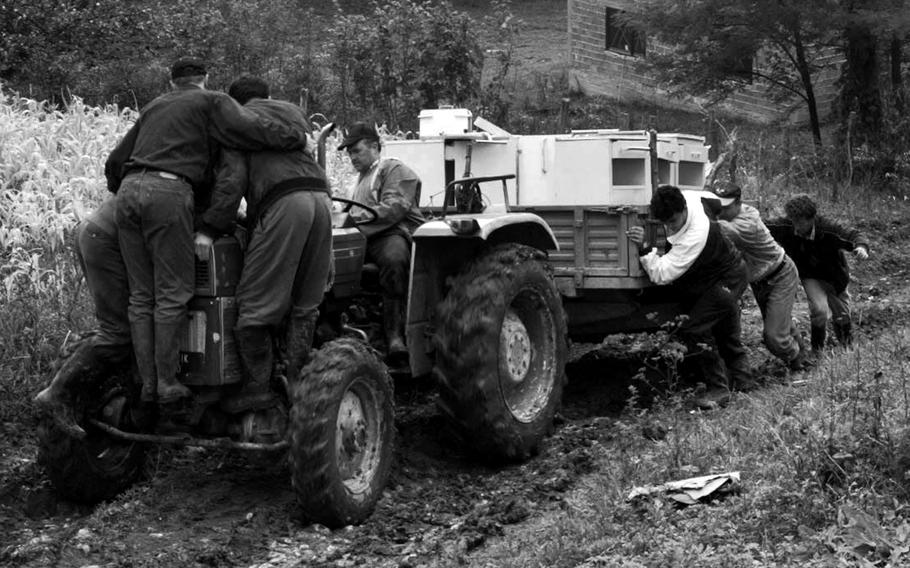 Bosnian Muslims labor to get a vehicle full of household goods and food supplies up a steep, muddy hill in Jusici in September, 1996.