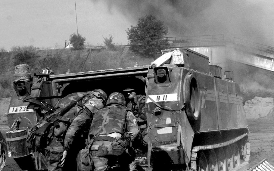 Engineers from B Co., 23rd Engineer Battalion, hunker down behind an armored vehicle as they shield themselves from debris following a blast as they destroy the war-damaged Sava River railroad bridge east of Brcko in September, 1996.