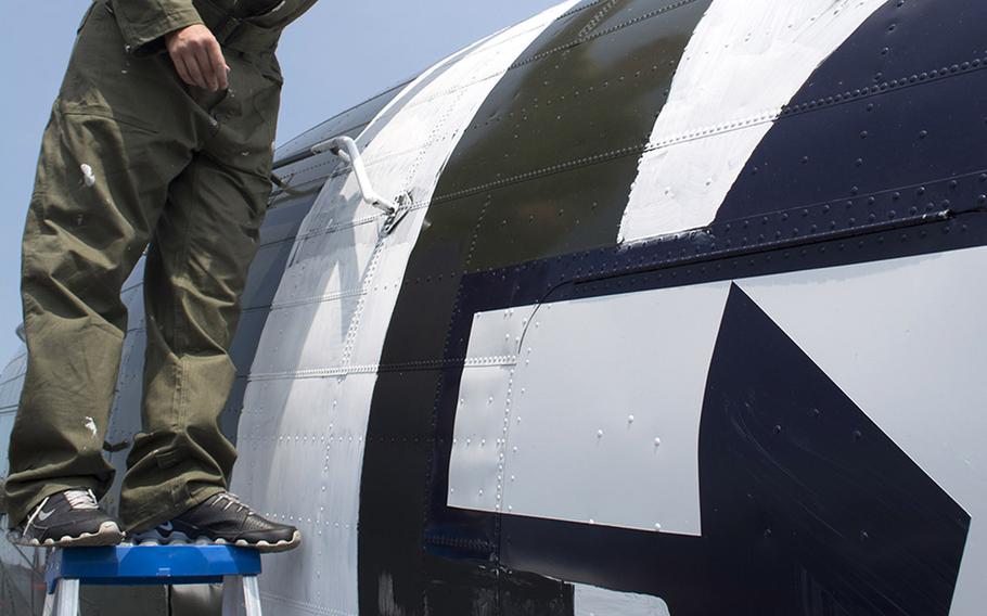A member of the Texas Flying Legends Museum paints stripes on a plane at the Culpeper Regional Airport Thursday, May 7, during the preview for the Arsenal of Democracy: World War II Victory Capitol Flyover.