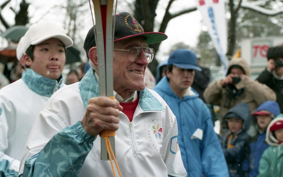 Louis Zamperini carries the Olympic torch through Naoetsu, Japan, in 1998.