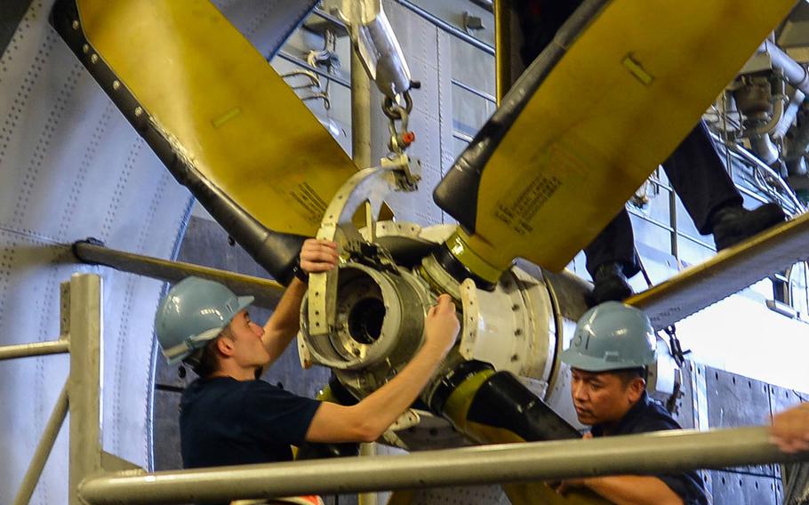 Sailors replace a propeller on the starboard side of an amphibious Landing Craft Air Cushion in the well deck of the USS San Diego while at sea in September 2014.