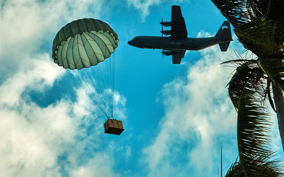 A bundle of humanitarian aid and Christmas presents airdrops onto Fais Island in the Federated States of Micronesia with a Royal Australian Air Force C-130J in the background Dec. 8, 2015. Excluding the nylon straps and duct tape used to secure the bundle together for safe transport in the aircraft, the bundle is made entirely of donated goods; from the contents to the plywood to the parachute which would otherwise be thrown away by the U.S. Army because the expiration date passed and is therefore unsafe for human use.