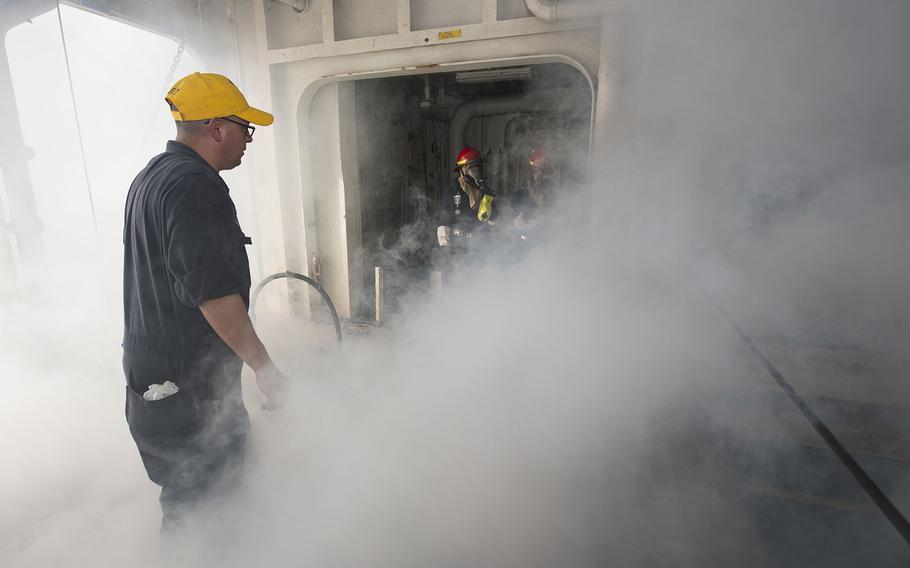 Damage Controlman 1st Class Daniel Moreno initiates a smoke machine during a fire drill aboard amphibious assault ship USS Boxer. 
