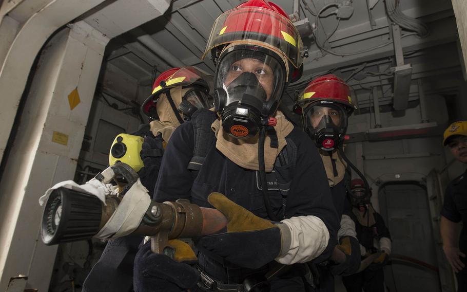 Sailors man a fire hose during a fire drill aboard amphibious assault ship USS Boxer. 