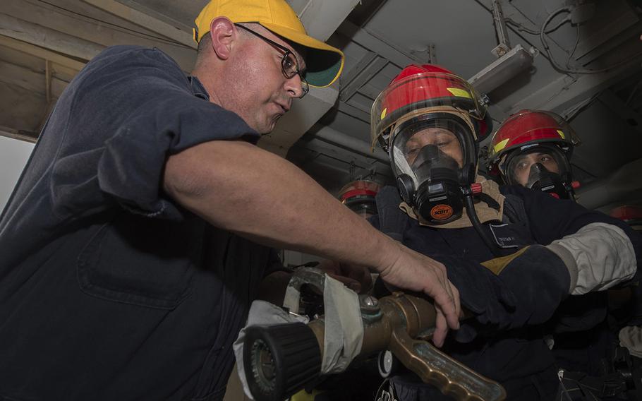 Damage Controlman 1st Class Daniel Moreno trains a fire team hose handling techniques during a fire drill.