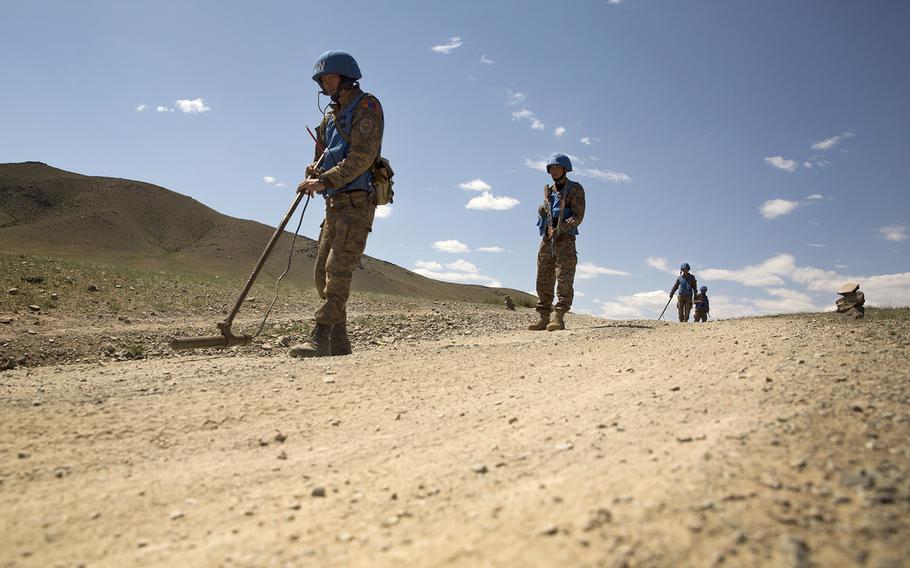 Members of the Mongolian Armed Forces sweep for mines to clear a path for their convoy.