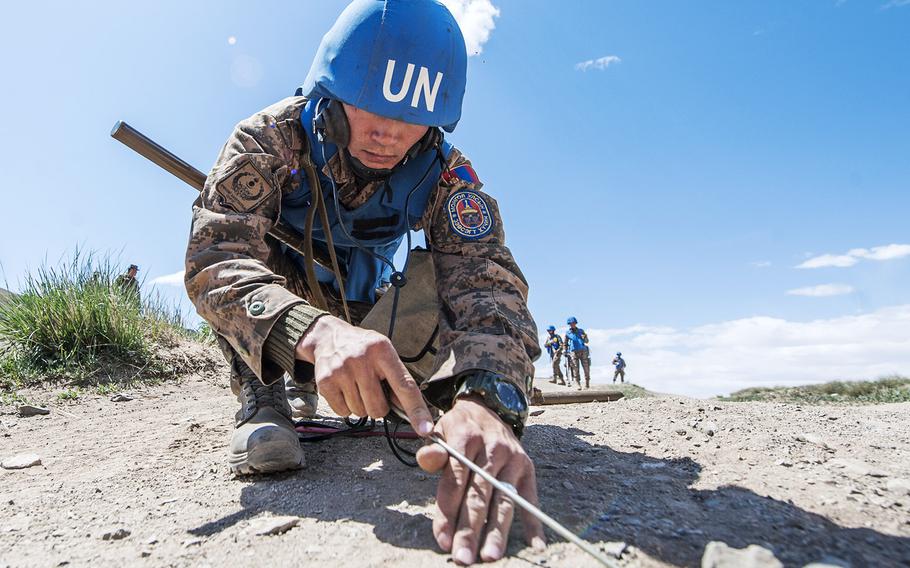  A soldier with the Mongolian Armed Forces marks an area after inspecting for land mines. 