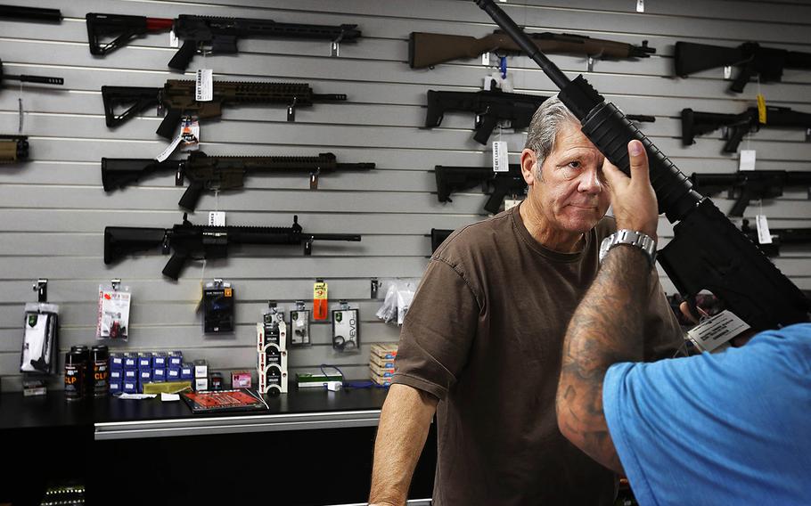 Gunsmith, Frank Cobet, of the Get Loaded gun store in Chino, Calif., shows a customer an AR-15 rifle on Tuesday, Dec. 8, 2015. 