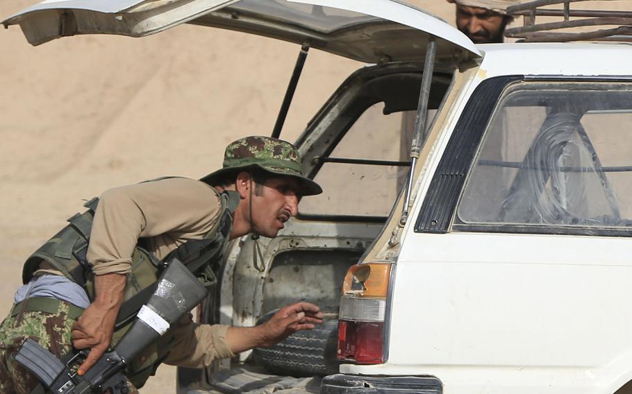 In a July, 2014 file photo, an Afghan National Army soldier inspects the trunk of a vehicle at a security vehicle checkpoint near the Shekasteh Tappeh village in Helmand province.