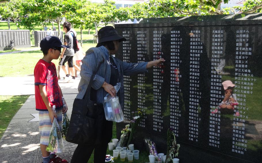 Yoshiko Maeshiro shows her 11-year-old grandson, Takuto, the name of her uncle at the Okinawa Peace Prayer Park Thursday, June 23, 2016. A ceremony was held to mark the 71st anniversary of the end of Battle of Okinawa.
 