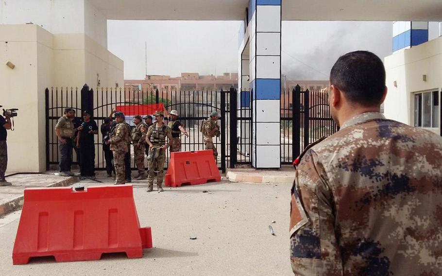 In this image taken by an Iraqi Counterterrorism Service photographer on Sunday, June 19, 2016, soldiers gather at the main gate of the hospital in Fallujah, Iraq after forces re-took the city center after two years of Islamic State control.