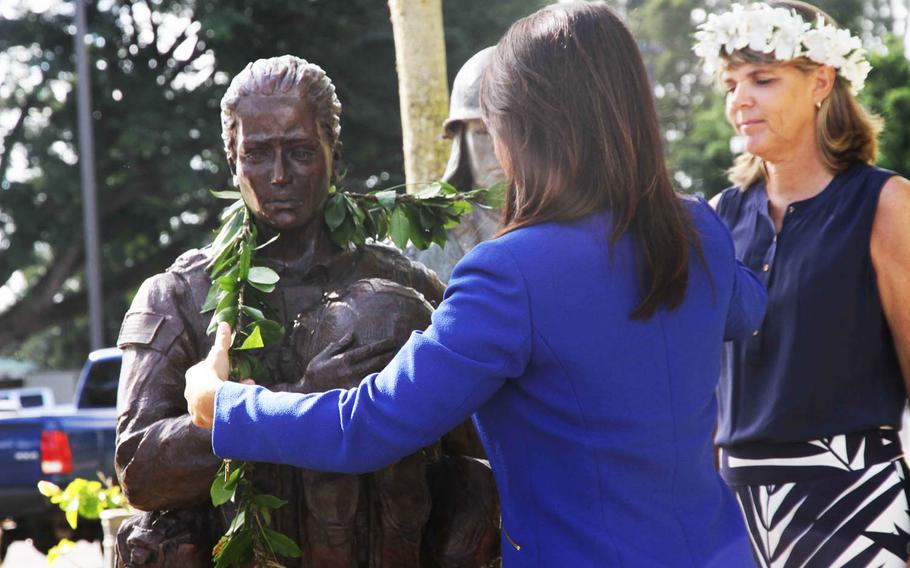 Rep. Tulsi Gabbard adjusts the ceremonial lei on the bronze statue of a female soldier, part of the "United by Sacrifice" monument at Schofield Barracks, Hawaii, Thursday, Oct. 6, 2016. Looking on is Lynn Weiler Liverton, the sculptor of the figure that is intended to represent all the women who have served in Hawaii's 25th Infantry Division.
