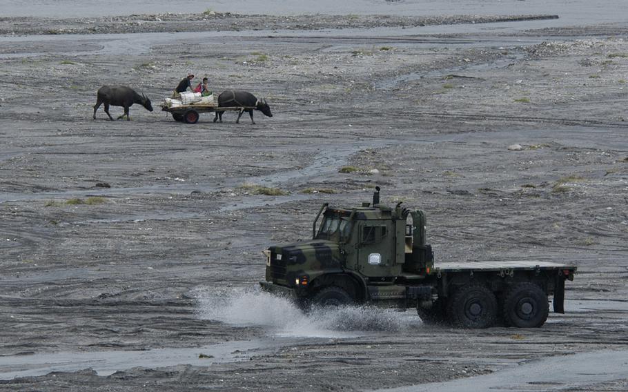 A mlitary vehicle passes farmers and water buffaloes in Crow Valley, Philippines on Monday. 