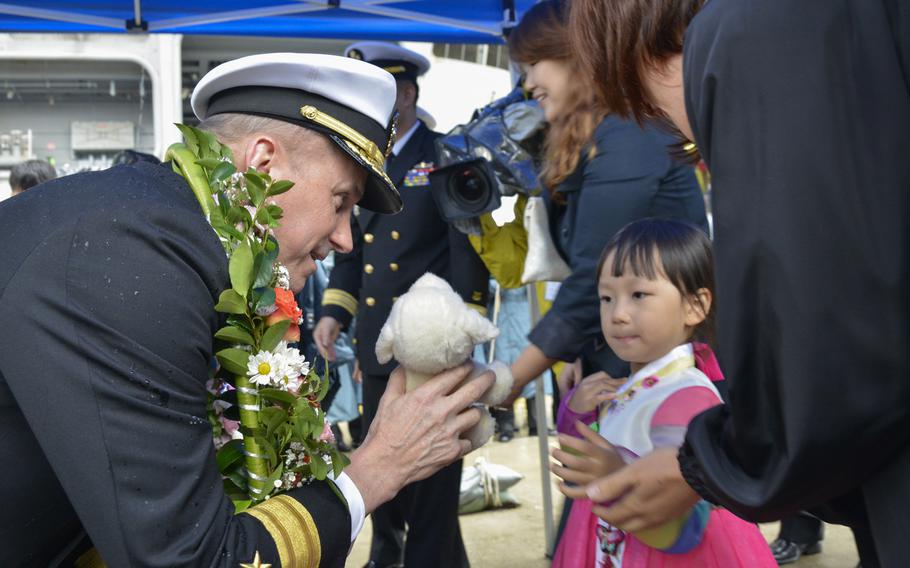 Rear Adm. Charles F. Williams, commander of Carrier Strike Group 5, embarked aboard Nimitz-class aircraft carrier USS Ronald Reagan, exchanges gifts with the daughter of a Republic of Korea sailor.
