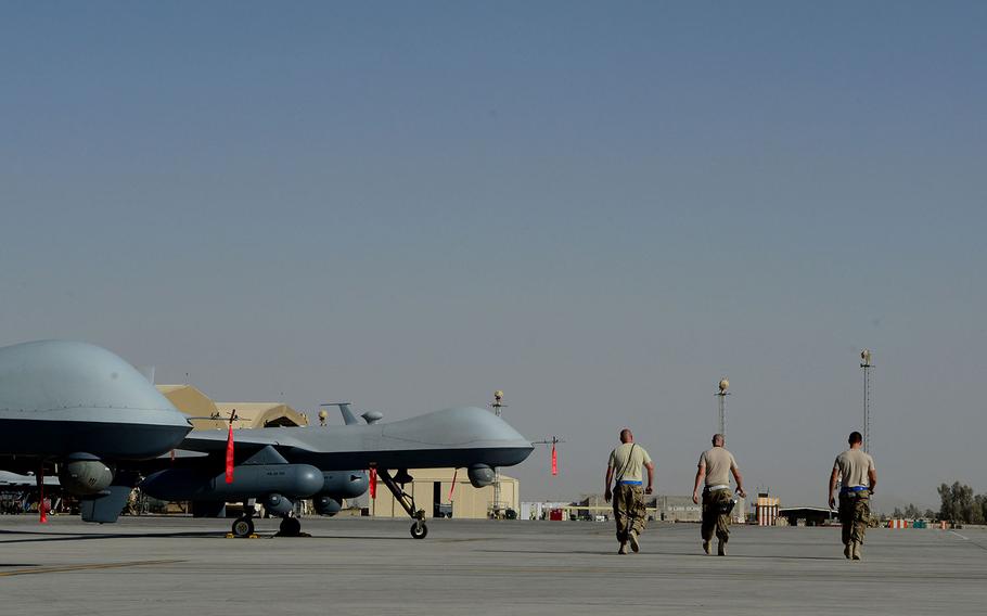 Airmen with the 451st Expeditionary Aircraft Maintenance Squadron aircraft armament systems specialists walk past MQ-9 Reapers with the 62nd Expeditionary Reconnaissance Squadron at Kandahar Airfield, Afghanistan on Aug. 18, 2014.