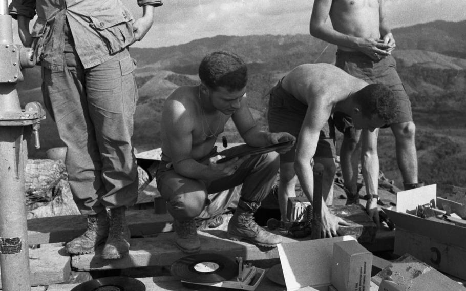 Marines stationed at the Rockpile shuffle through a record collection, looking for some form of entertainment while sitting atop the giant rock formation in November 1966. 