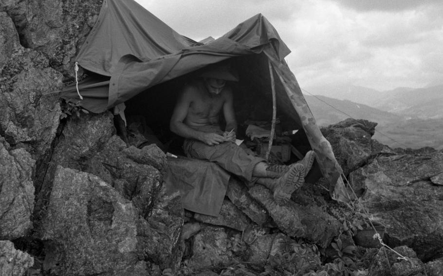 The Rockpile, a 750-foot high rocky formation in Vietnam, was the site of an entrenched American presence in 1966. Here, a Marine writes a letter from atop the outcropping in November 1966.