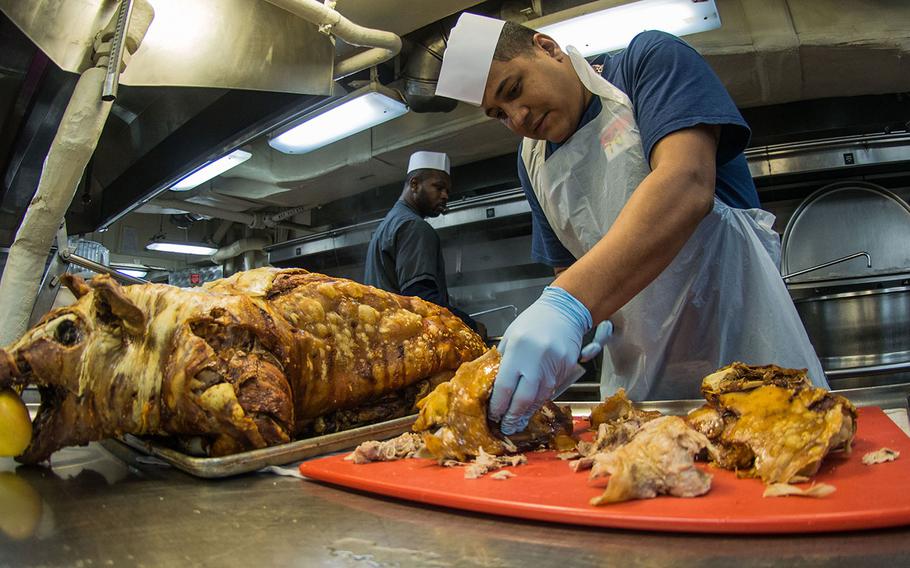 Petty Officer 1st Class Carlos Aruz cuts cooked pig in the galley on Nov. 24, 2016 in Yokosuka, Japan, during a Thanksgiving meal with shipmates and family members on the aircraft carrier USS Ronald Reagan.
