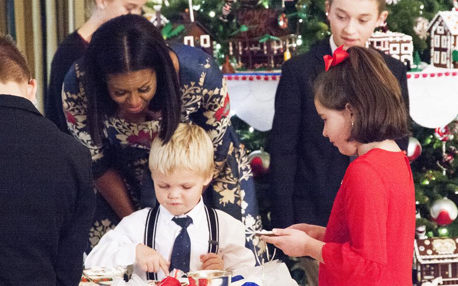 First Lady Michelle Obama admires a boy's decorating of a cookie at the White House on Nov. 29, 2016. Obama invited military families to the White House to preview holiday decorations.