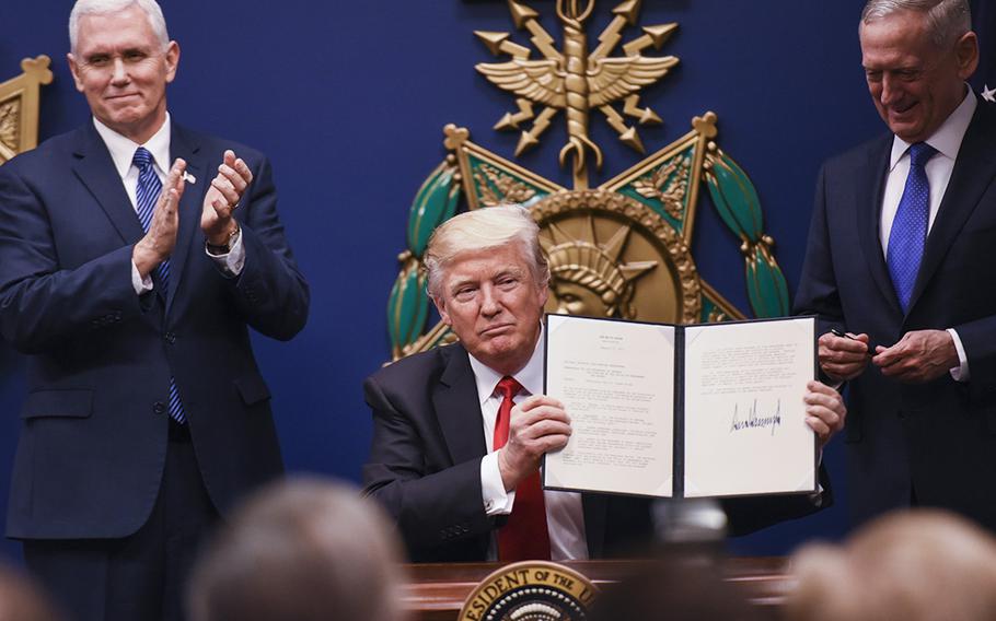 Vice President Mike Pence and Defense Secretary Jim Mattis look on as President Donald Trump holds up an executive order to increase military readiness that he signed Friday at the Pentagon.