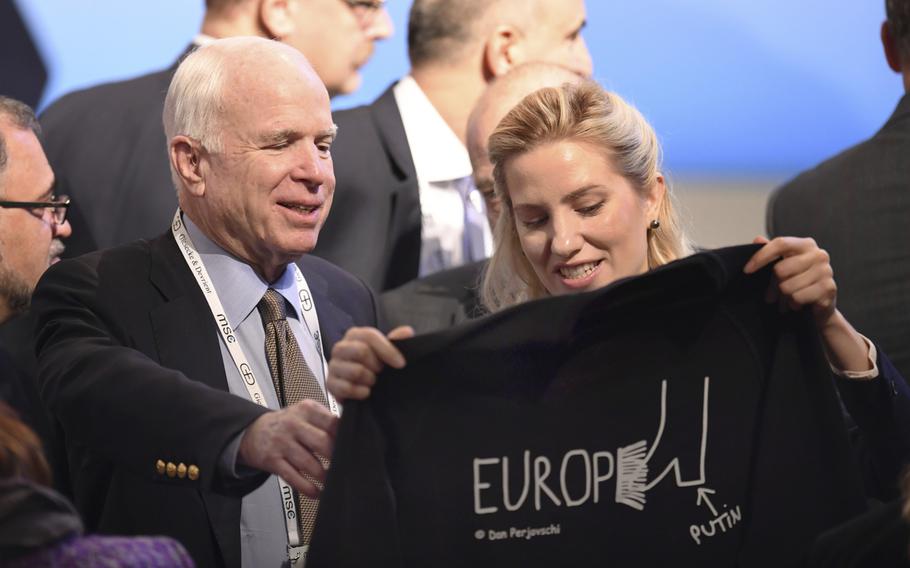 U.S. Senator John McCain, left, smiles as he gets a t-shirt by Ukrainian journalist and politician Svitlana Zalishchuk on the last day of the Munich Security Conference in Munich, southern Germany, Sunday, Feb. 19, 2017. 