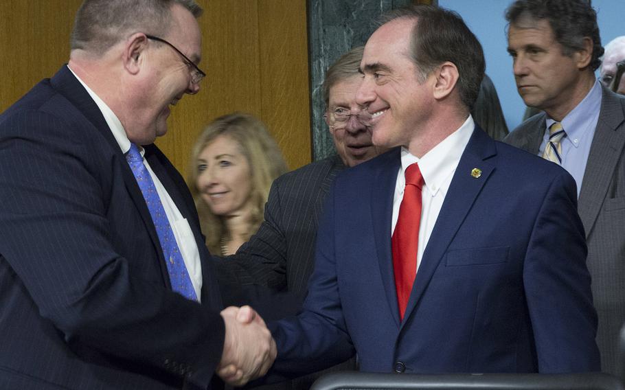 Sen. Jon Tester, D-Mont., left, shakes hands with Dr. David Shulkin before Shulkin's confirmation hearing as VA secretary in February, 2017. Tester and Sen. Sherrod Brown, D-Ohio, right, are among eight Democrats who signed a letter to Shulkin asking for more details about VA's plan to provide urgent mental health care to veterans with other-than-honorable discharges.