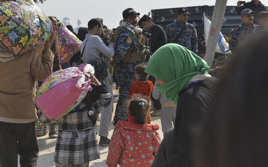 A man and a girl carry bags full of their belongings as they walk toward a truck that will take them to a displacement camp on Wednesday, March 8, 2017. Civilians fleeing violence in Mosul, Iraq were being packed into vehicles and taken to screening points, then on to the camps. Thousands are fleeing each day as fighting intensifies in the western half of the city.