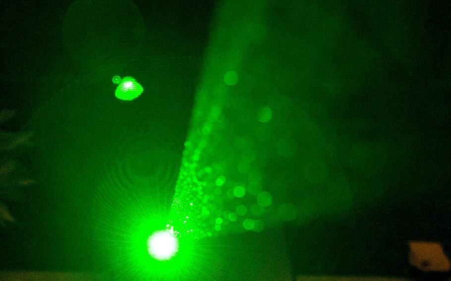A high-powered laser pointer is pointed skyward.