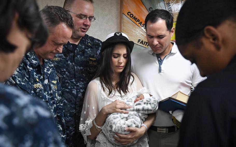 Tania Rodriguiz Ramos holds her baby Sara Victoria Llull Rodriguiz, as sailors aboard the Military Sealift Command hospital ship USNS Comfort (T-AH 20) say a prayer. The infant was the first child born aboard the Comfort in more than seven years. Ramos was evacuated to the ship when she was unable to get adequate medical care on Puerto Rico after Hurricane Maria devastated the island.