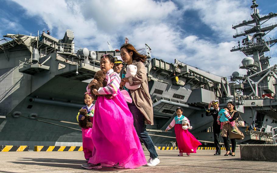 South Korean girls in traditional dress walk by the USS Ronald Reagan at Busan, South Korea, Saturday, Oct. 21, 2017. 