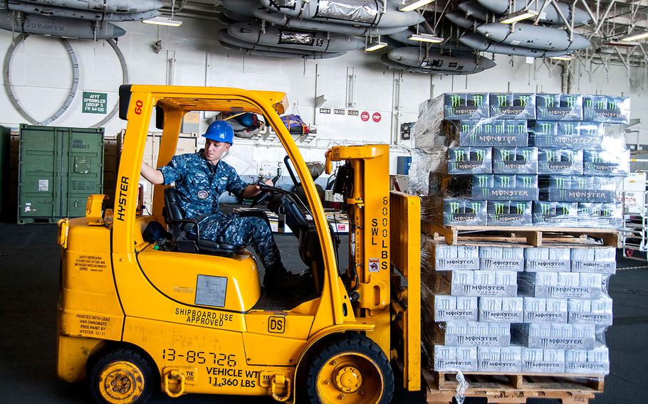 Petty Officer 3rd Class T. A. Sharp moves pallets of energy drinks through the hangar bay of the aircraft carrier USS Harry S. Truman in Norfolk, Virginia on Aug. 17, 2015.