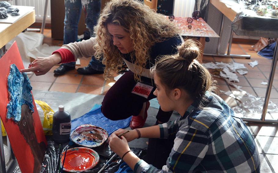 Instructor Jessica Mitchell and Wiesbaden's Becca Adams discuss one of her pieces in the mixed media workshop at DODEA-Europe's Creative Connections, Wednesday, Nov. 1, 2017.

