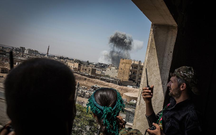 Syrian Democratic Forces soldiers look at smoke rising after an air attack while battles against Islamic State continue in Raqqa, Syria, on Aug. 12, 2017. 