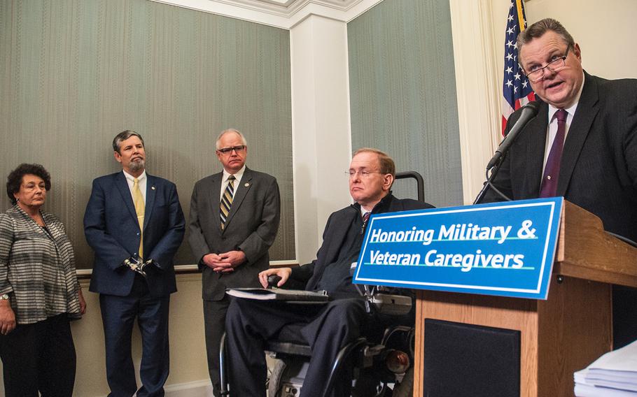 Sen. Jon Tester, D-Mont. attends a briefing at the Capitol in Washington, D.C., on Wednesday, Dec. 6, 2017, as lawmakers and veterans representatives gathered to urge the passage of legislation that would expand benefits for veterans' caregivers. At left are U.S. Rep Jim Langevin, D-R.I., in a wheelchair, U.S. Rep. Tim Walz, D-Minn. and quadruple amputee Dave Riley, a military veteran who contracted a bacterial infection in 1997, went into a coma and subsequently lost all four limbs. Riley's wife Yvonne, at far left, has been her husband's primary caregiver for two decades.