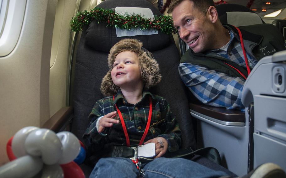 Three-year-old James Anthony Lindh III, nicknamed Tripp, sits next to his father, Army Lt. Col. Tony Lindh, as they look out the window of a Boeing 777 prior to taking off on United Airlines' Fantasy Flight to the "North Pole" at Washington-Dulles International Airport in Virginia on Saturday, Dec. 9, 2017.