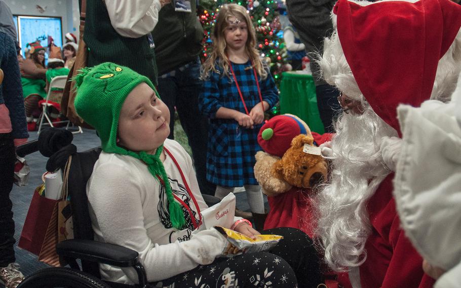 After deplaning from United Airlines' Fantasy Flight to the "North Pole," cancer patient Elaina Stover, 9, wearing a green Grinch hat greets Santa Claus at Washington-Dulles International Airport in Virginia on Saturday, Dec. 9, 2017.