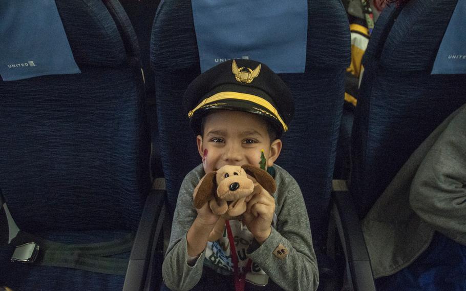 Jordan LaRocco, 7, borrows a pilots hat as he takes a seat aboard a Boeing 777 airplane prior to taking off on United Airlines' Fantasy Flight to the "North Pole" at Washington-Dulles International Airport in Virginia on Saturday, Dec. 9, 2017.