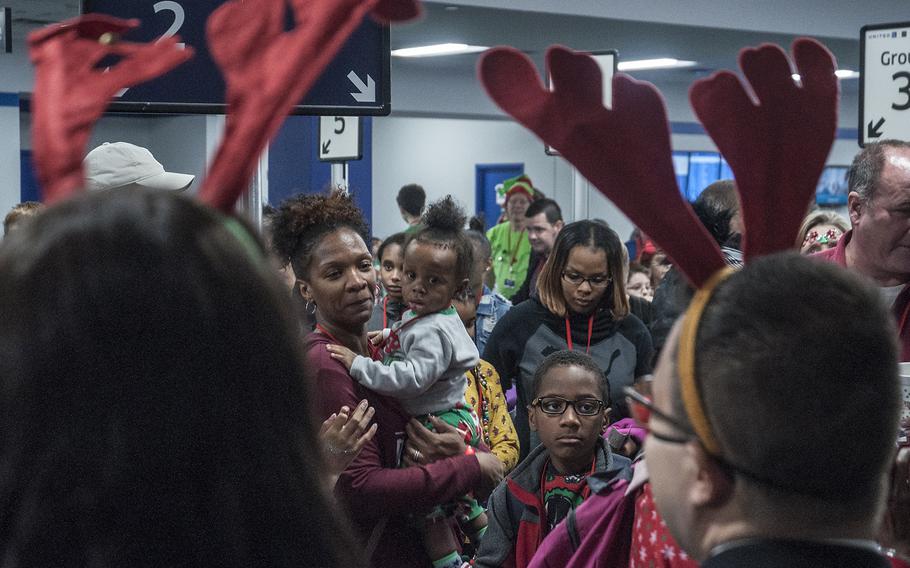 Families receive assistance from United Airlines employees wearing reindeer antler head gear prior to boarding Fantasy Flight to the "North Pole" at Washingoton-Dulles International Airport in Virginia on Saturday, Dec. 9, 2017.