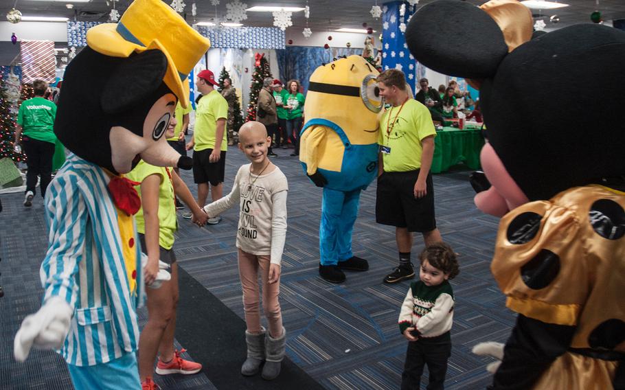 Cancer patient Addy Flint, 9, smiles as she holds hands and dances with costumed Disney characters following a flight on United Airlines' Fantasy Fight to the "North Pole," at Dulles International Airport in Virginia on Saturday, Dec. 9, 2017.