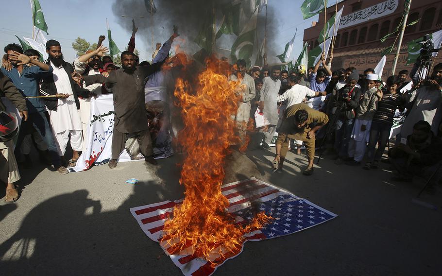 Supporters of Pakistani religious groups burn a representation of an American flag at a rally to condemn a tweet by U.S. President Donald Trump, in Karachi, Pakistan, Tuesday, Jan. 2, 2018. 
