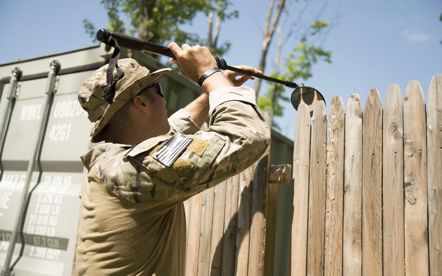 Maj. Daniel O'Neil, from 158th Fighter Wing Explosive Ordnance Disposal, sweeps a fence with a mirror to see what is behind it during a training scenario at the Ethan Allen Firing Range, Jericho, Vt., May 27, 2015.