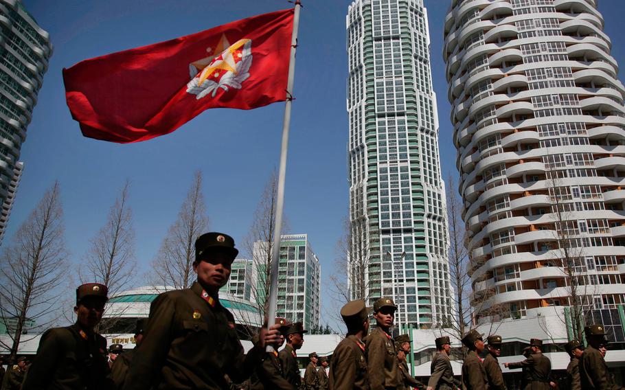 North Korean soldiers carry the Korean People's Army flag as they walk past residential buildings along Ryomyong street, in Pyongyang, North Korea, on April 13, 2017.