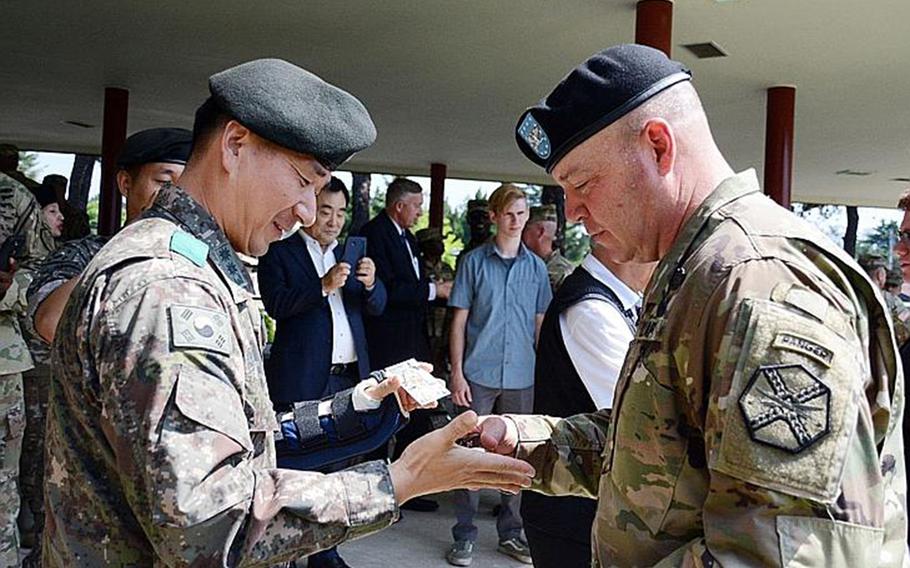 South Korean Sgt. Maj. Choe Jin-han, left, receives a coin from Col. Brandon Newton, garrison commander of Camp Red Cloud and other bases north of Seoul, South Korea, after showing him a photo after the garrison's inactivation ceremony, Thursday, June 21, 2018. 
