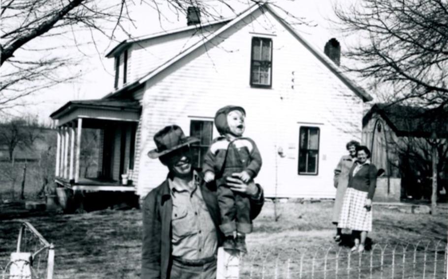 U.S. Army 1st Lt. Garlin M. Conner with his son, Paul, at his parents' home.  Conner's wife Pauline (left) and sister-in-law Thelma (right) are standing in the background.