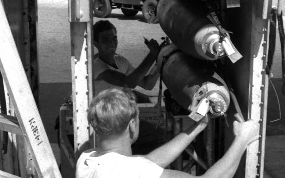 Bombs attached beneath the wing of a B-52 at U-Tapao Royal Thai Navy Airfield are prepared before a mission over Southeast Asia in January, 1970.